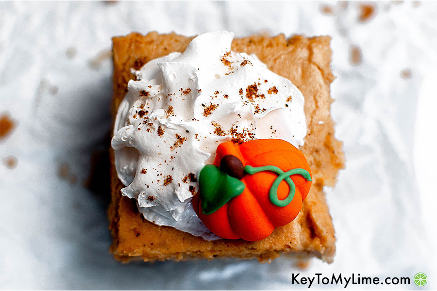 A pumpkin pie cheesecake bar topped with whipped cream.