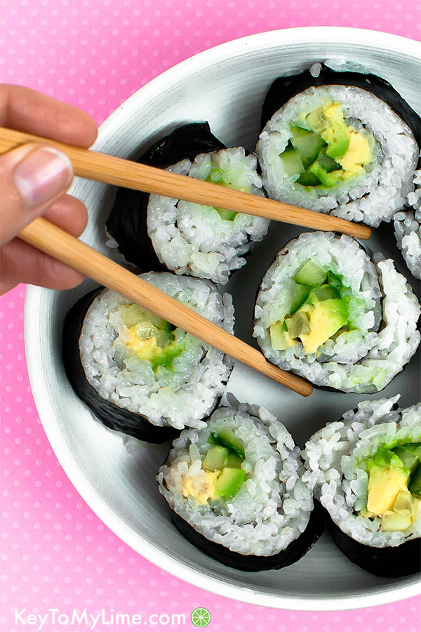 Vegan sushi filled with red bell pepper, carrot, cucumber, and avocado in a bowl.