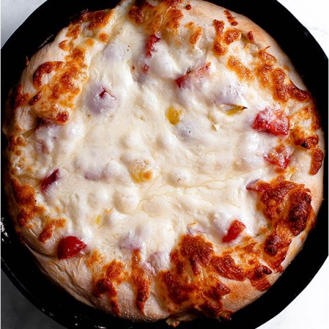 Gluten free pizza crust with cheese in a cast iron skillet.