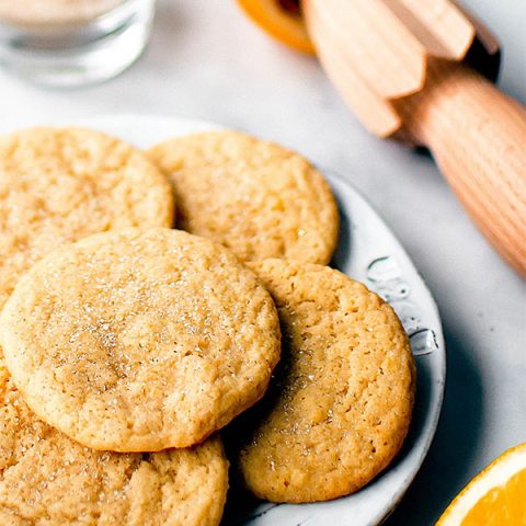 Lemon sugar cookies on a plate surrounded by ingredients.