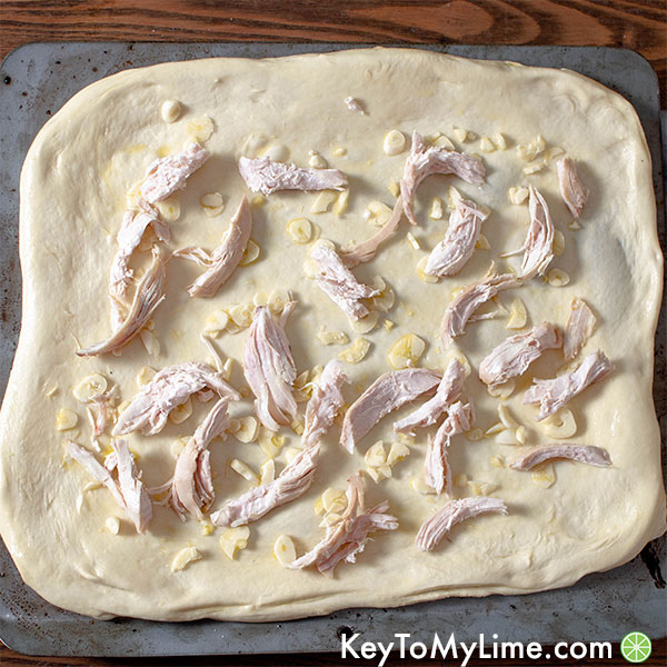 Pizza dough with olive oil, chicken, and garlic.