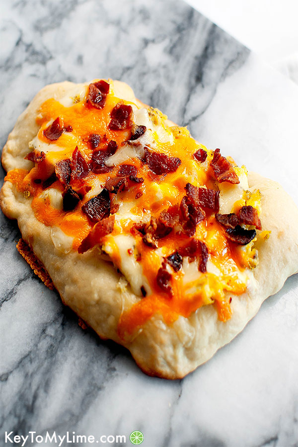 Breakfast pizza with bacon, cheese, and scrambled eggs.