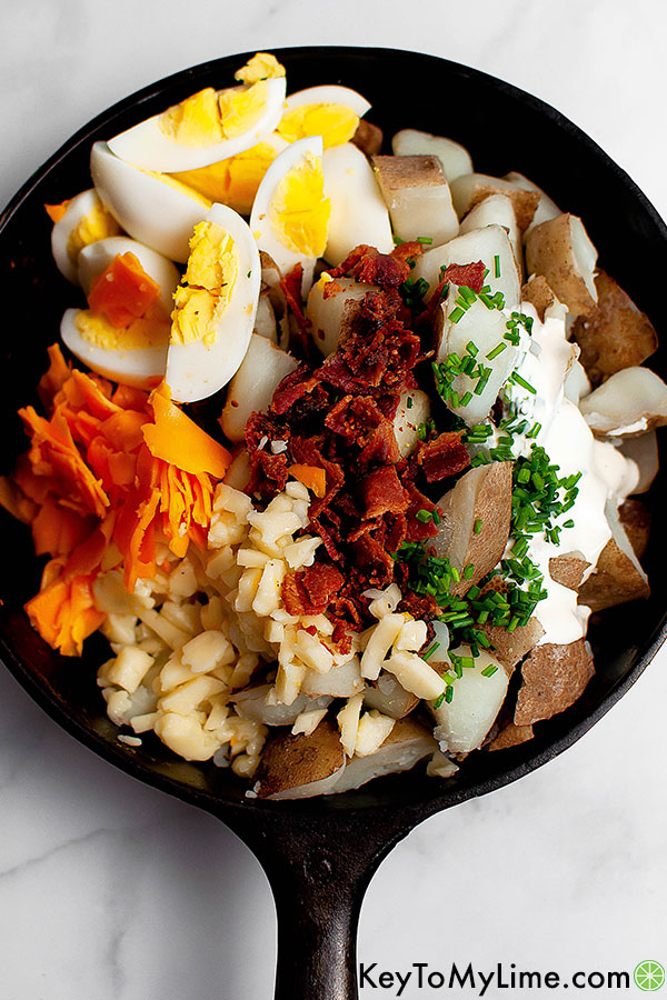 The ingredients for loaded baked potato salad displayed in a bowl.