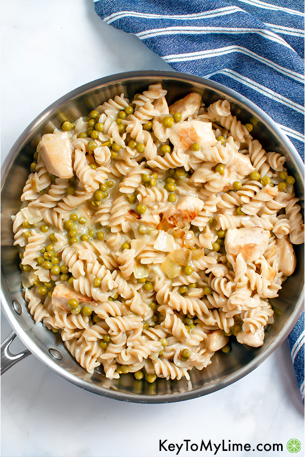Pasta with chicken and peas in a silver skillet.