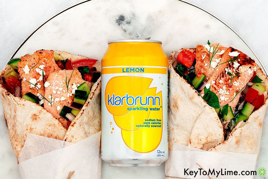 An overhead image of two gyros on a marble board with a can of lemon Klarbrunn sparkling water.