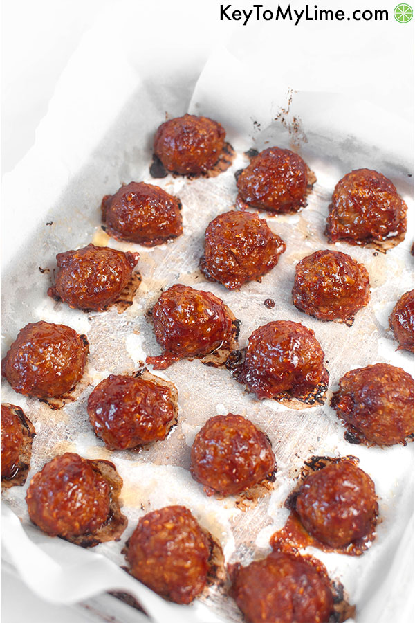 A parchment paper lined baking sheet with cooked bbq turkey meatballs.