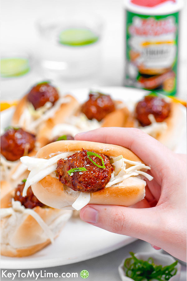 A hand holding a cajun bbq meatball slider with lime slaw.