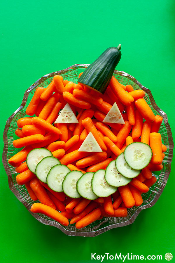 A close up image of the Jack-o'-Lantern made out of carrots and cucumber slices.
