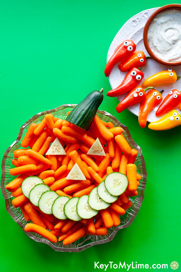 A Halloween themed vegetable tray with a carrot pumpkin and sweet pepper ghosts.
