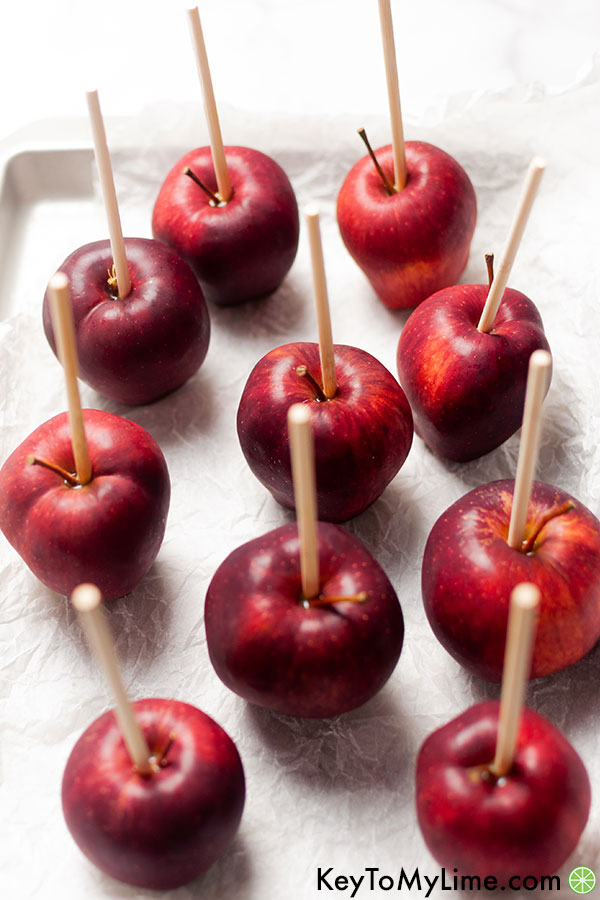 Red delicious apples with a stick in each ready to be dipped in chocolate.