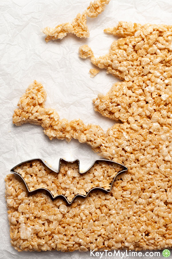 A cookie cutter cutting out shapes in rice krispie treats.