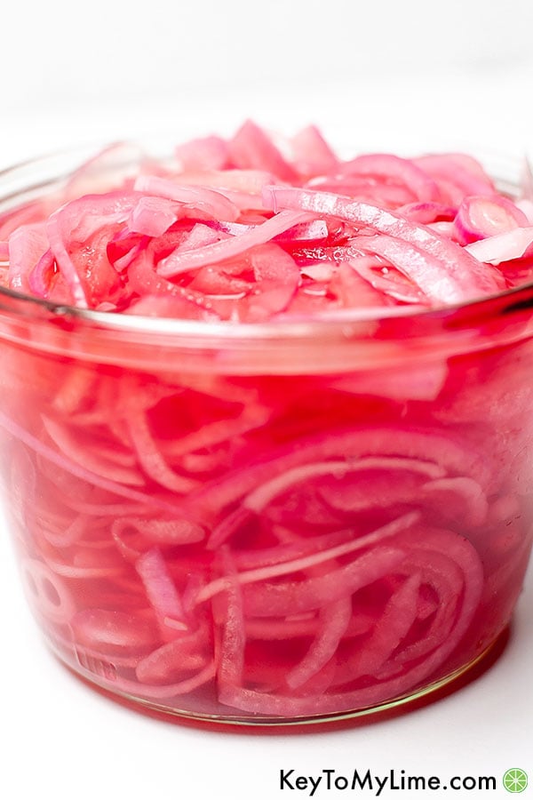 A close up of quick pickled onions through the glass jar.