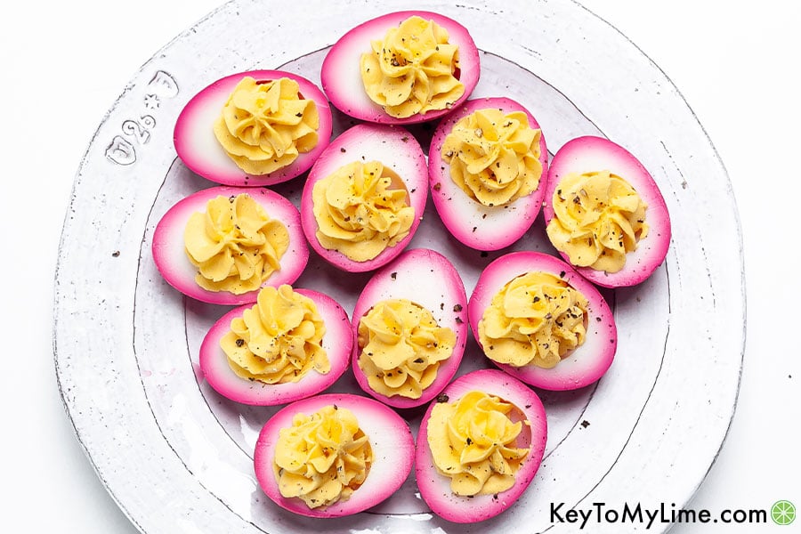 Beet dyed deviled eggs topped with freshly cracked pepper.