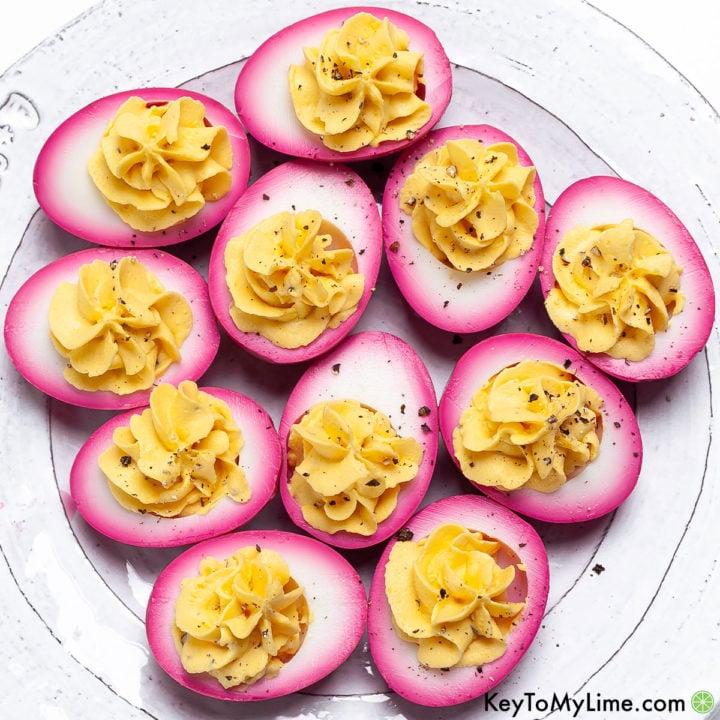 An overhead image of beet pickled deviled eggs on a white plate.