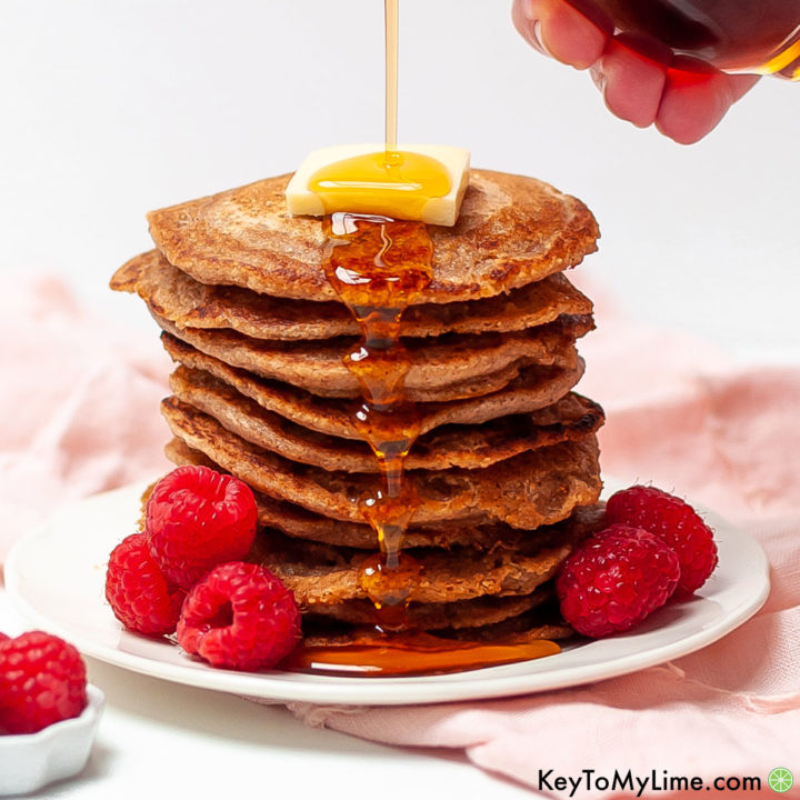 Vegan oat flour pancake stack with butter, syrup, and fresh raspberries.