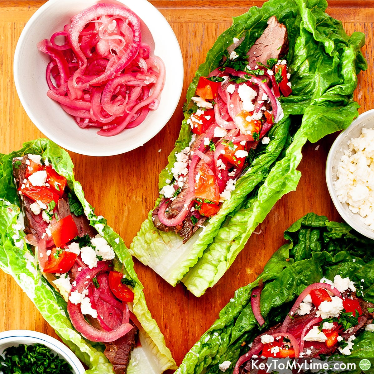 The best steak lettuce wrap recipe on a wood board next to toppings.