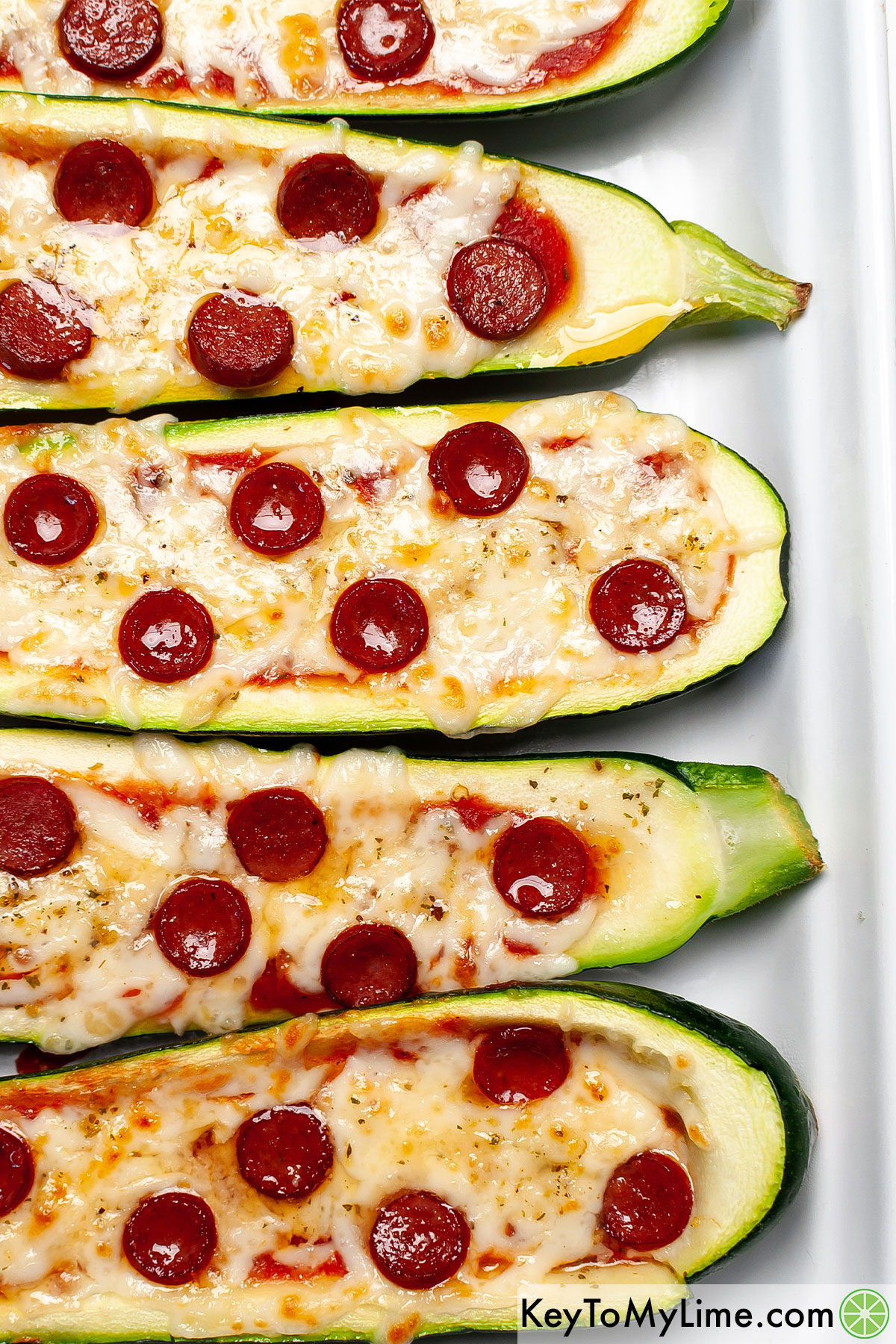 A close up image of pepperoni zucchini pizza boats.