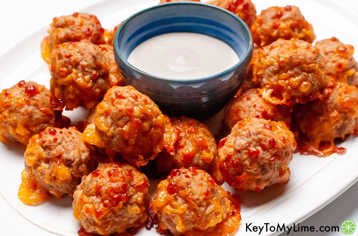 Sausage balls on a platter surrounding a cup of ranch.