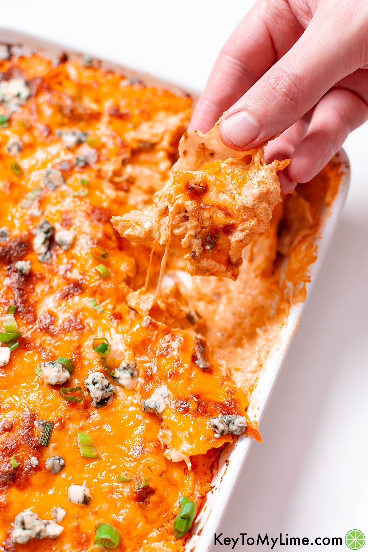 Taking a scoop of buffalo chicken dip with a tortilla chip.