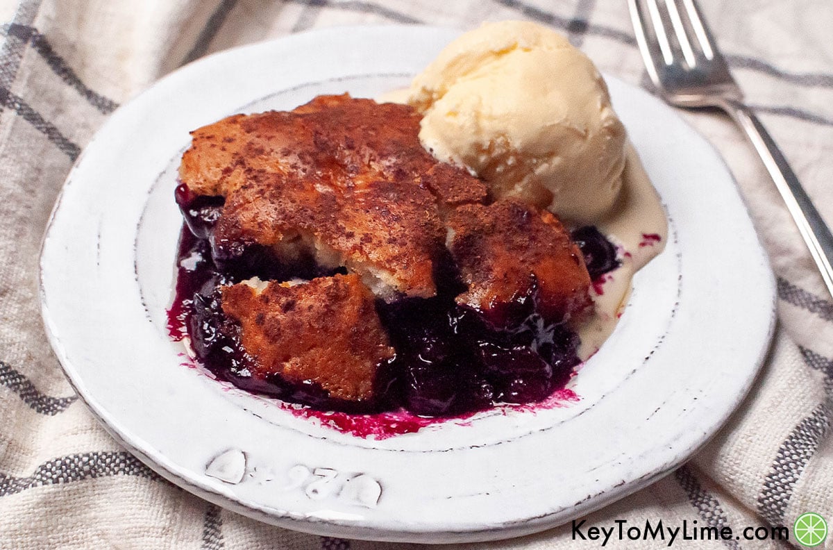 Bisquick blueberry cobbler on a plate with a scoop of vanilla ice cream.