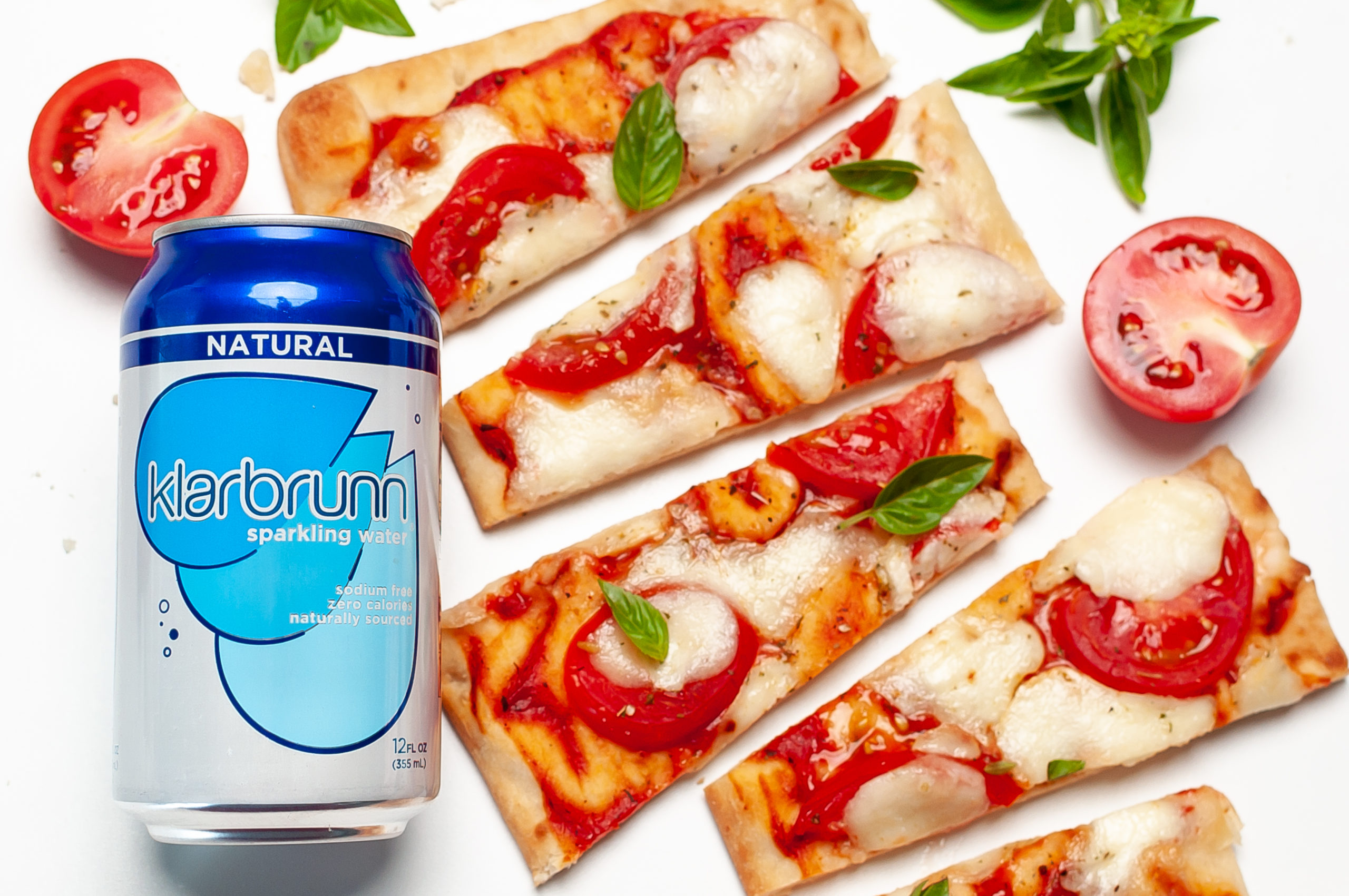 Flatbread pizza next to a can of Klarbrunn.