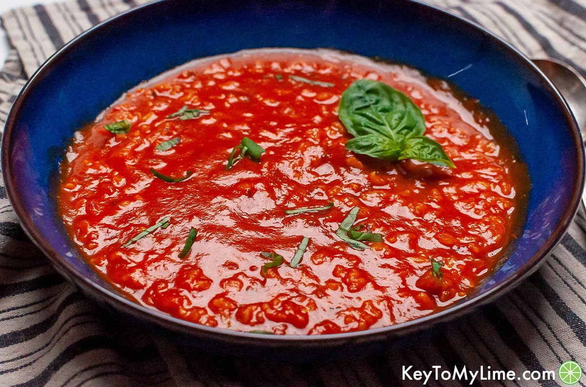 A side image of a bowl of tomato rice soup showing the light glistening off the top of the soup.