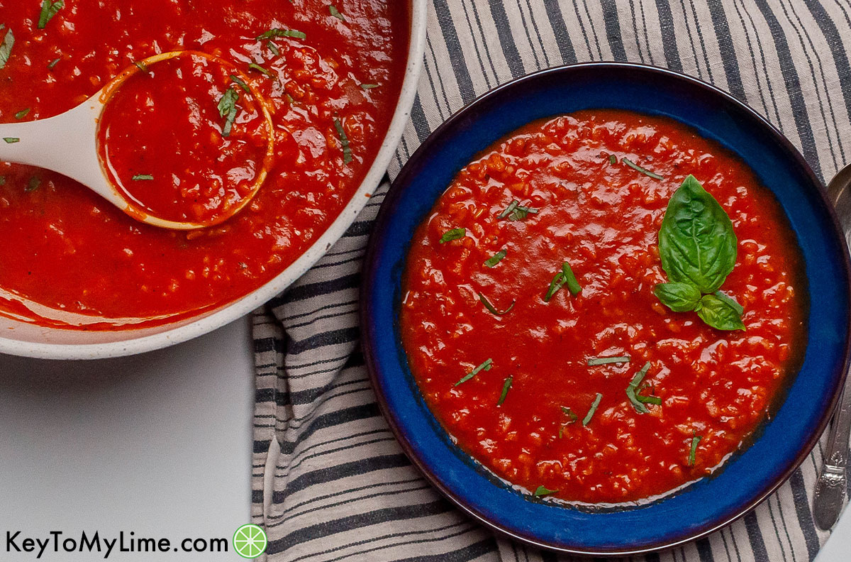 A pot of tomato rice soup next to a bowl of it.