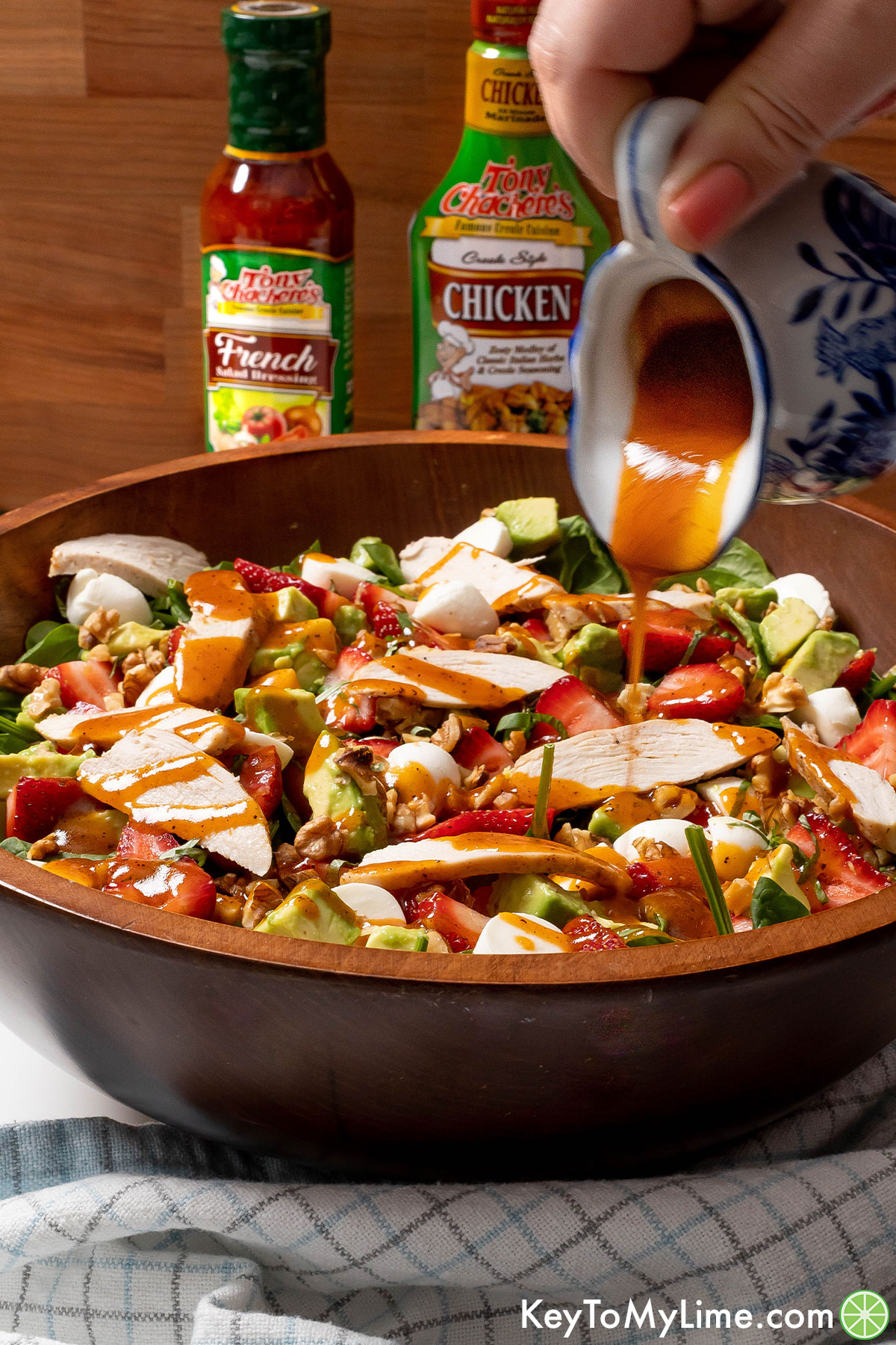 Pouring French dressing onto strawberry chicken salad.