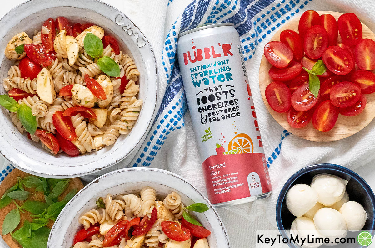 Bowls of caprese pasta salad next to a can of BUBBL'R sparkling water.