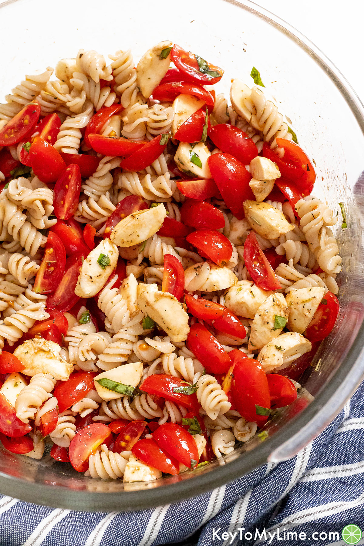 A close up image of a large bowl of caprese pasta salad.