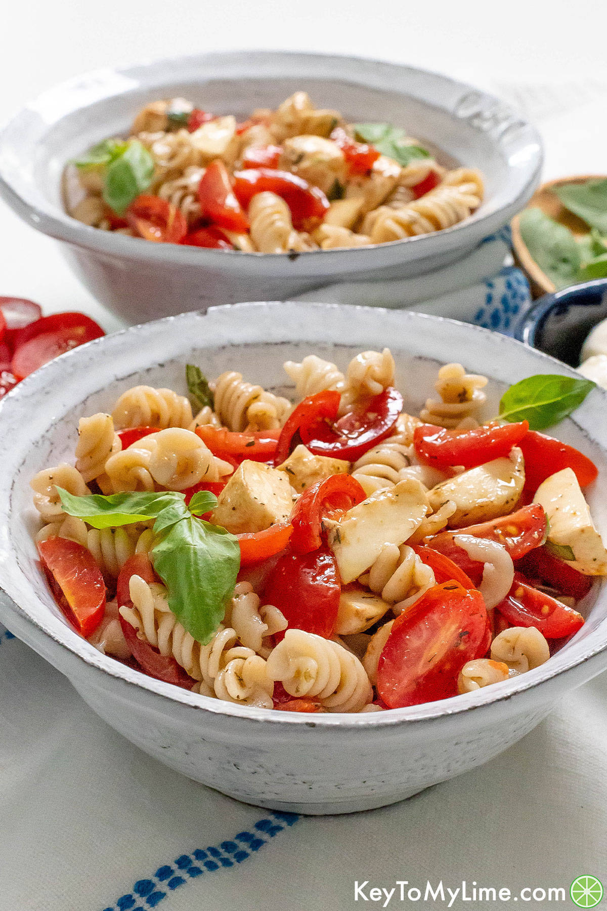 A side image of two bowls of caprese pasta salad.