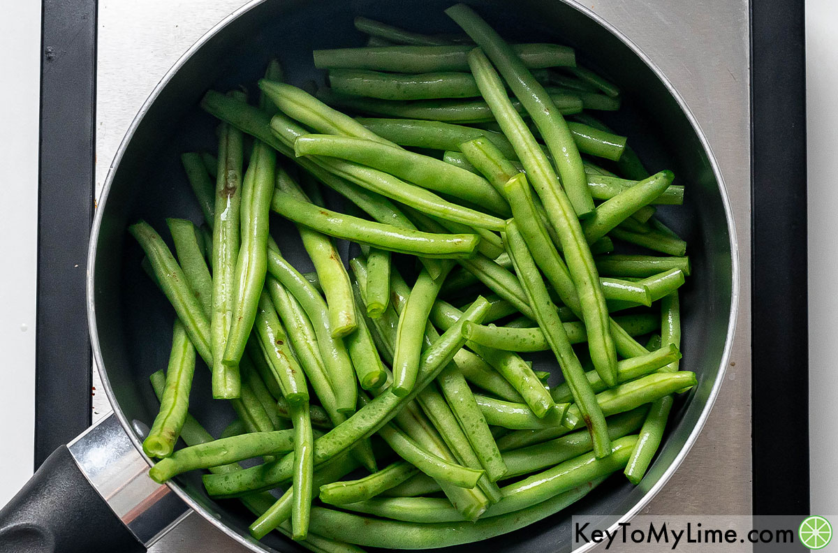 An image of trimmed green beans in a skillet.