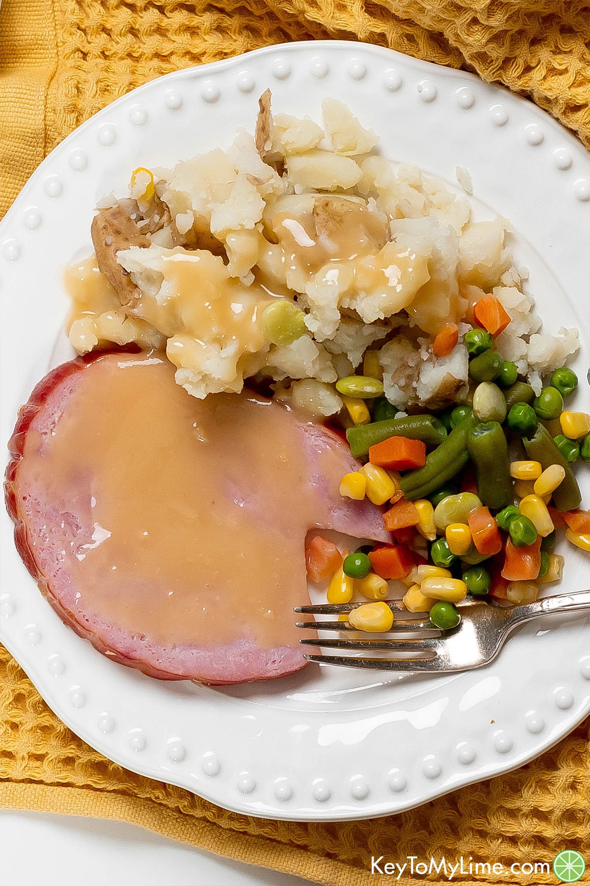 An overhead picture of a Christmas ham dinner with gravy throughout.