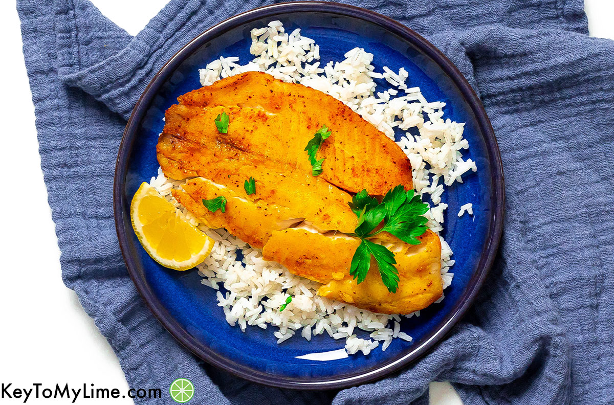 An overhead image of plated air fryer tilapia on top of a bed of rice.