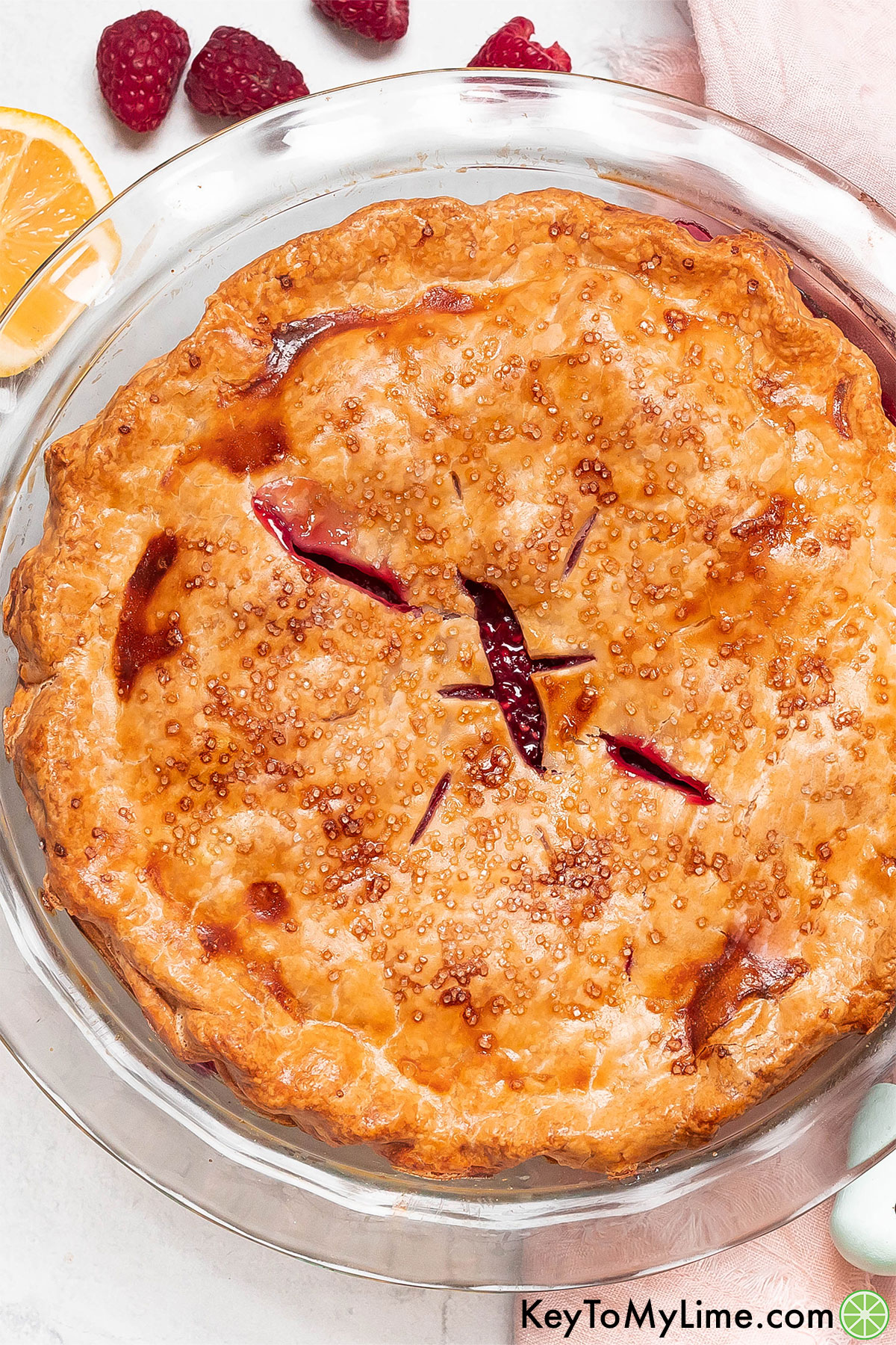 A golden brown pie with thick raspberry filling inside a pie dish.
