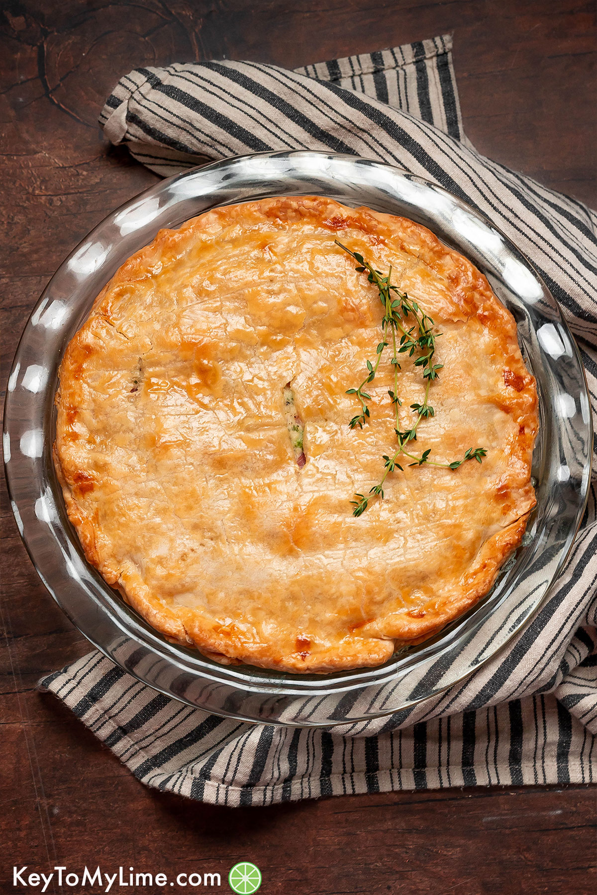 A whole ham pot pie served in a glass pie dish with a golden brown crust.