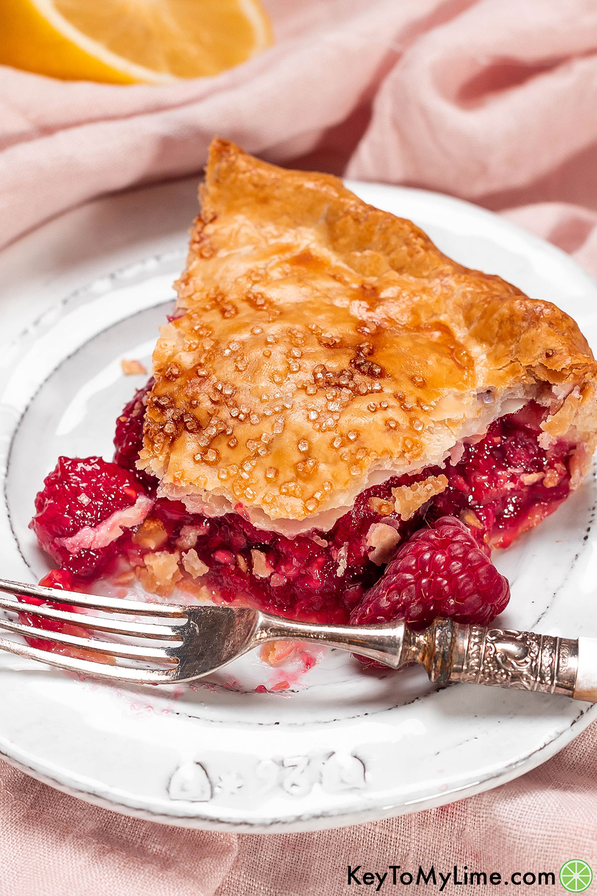 A close up shot of a slice of raspberry pie with a bite missing.