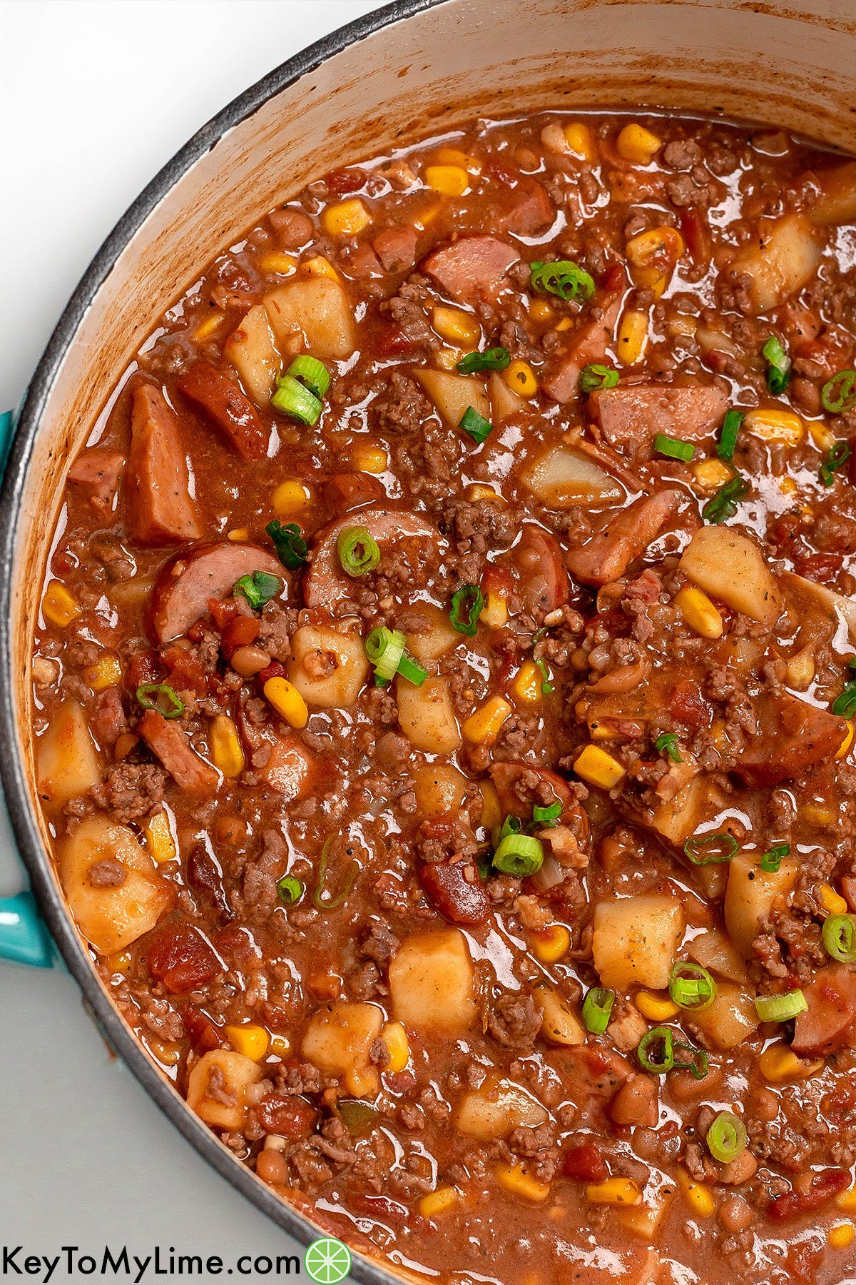 An overhead shot of hearty cowboy stew with vibrant corn and green onions.
