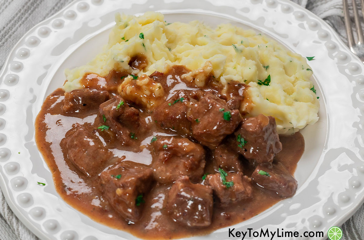 A side shot of beef tips served with mashed potatoes.