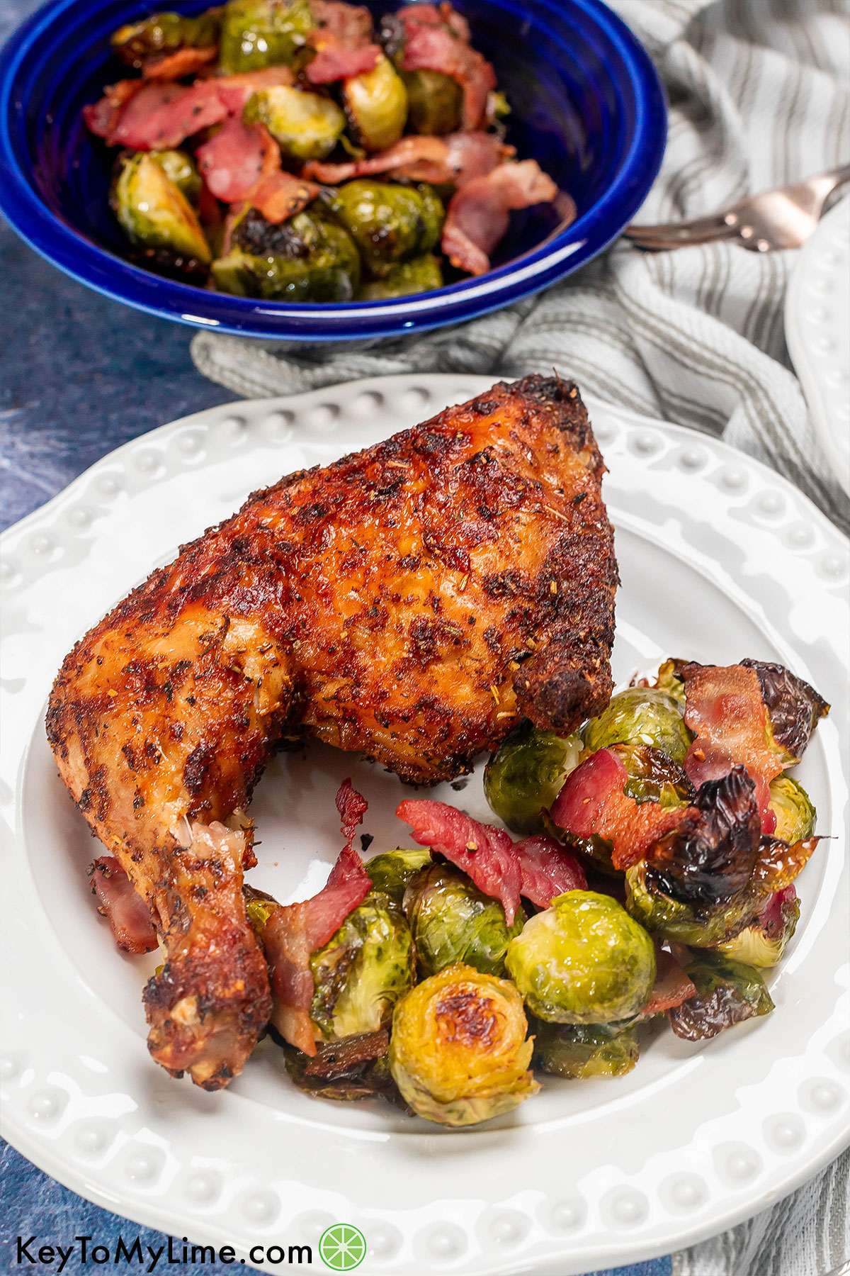 A crispy seasoned chicken quarter with a side of brussel sprouts and crispy bacon pieces throughout.