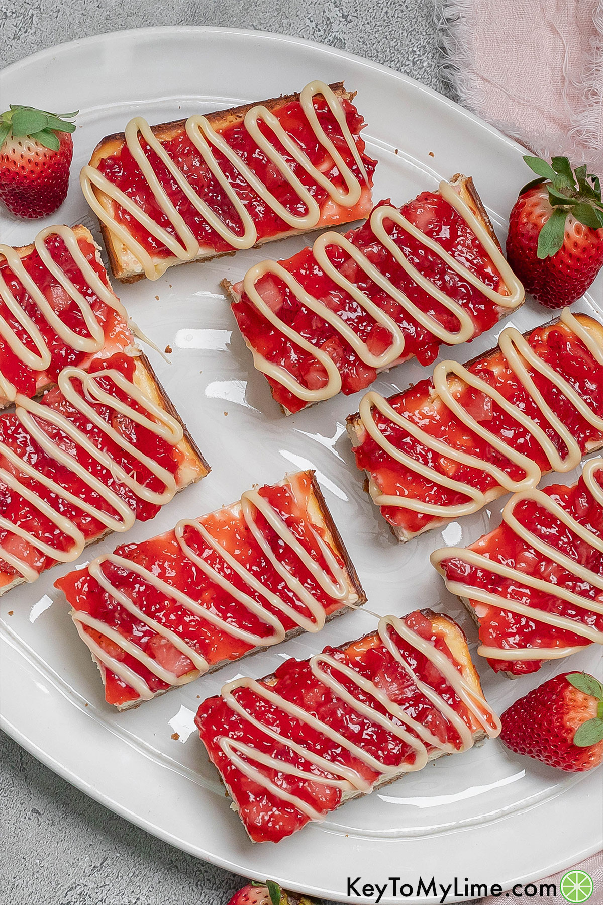 An overhead shot of cut up cheesecake bars spread out evenly on a large platter.