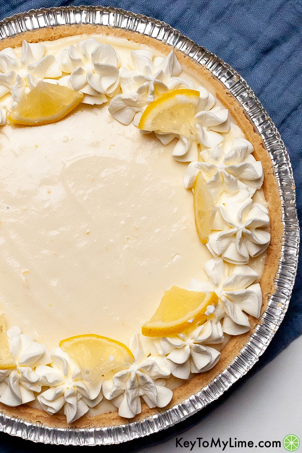 A delicious glistening lemon pie in a pie dish garnished with fresh toppings.