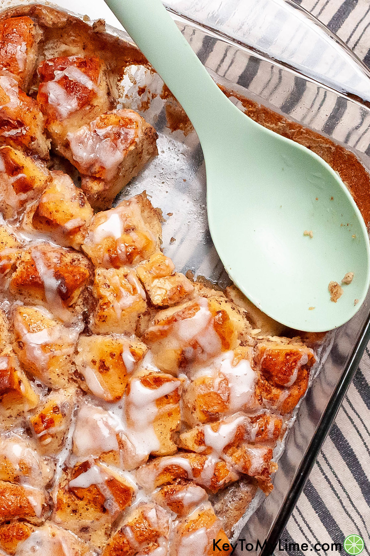 A cinnamon roll casserole dish with a large serving spoon inside.
