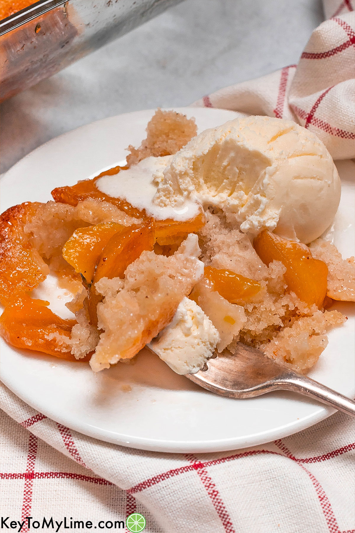 A serving of peach cobbler with a bite missing on a small white plate.