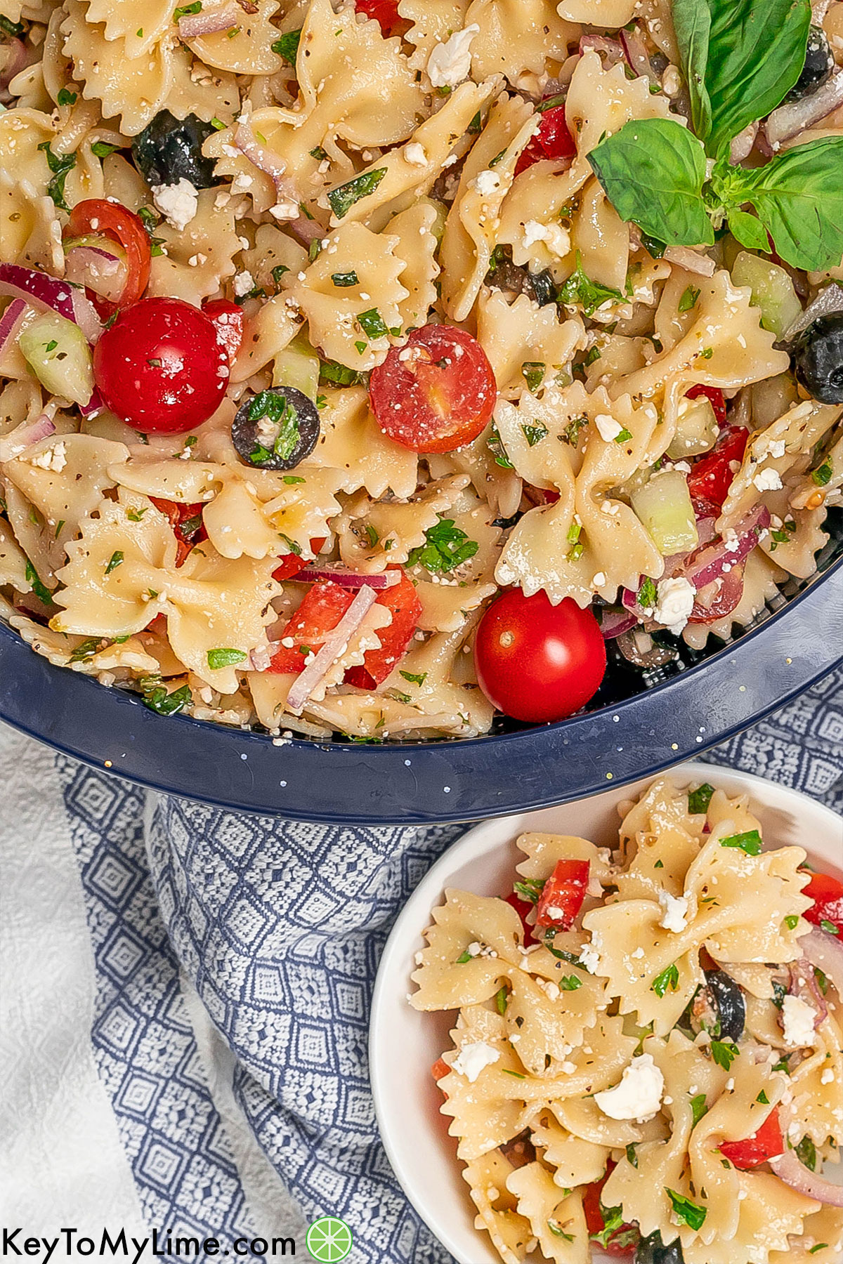 An overhead image of pasta salad garnished with fresh tomatoes and feta cheese.