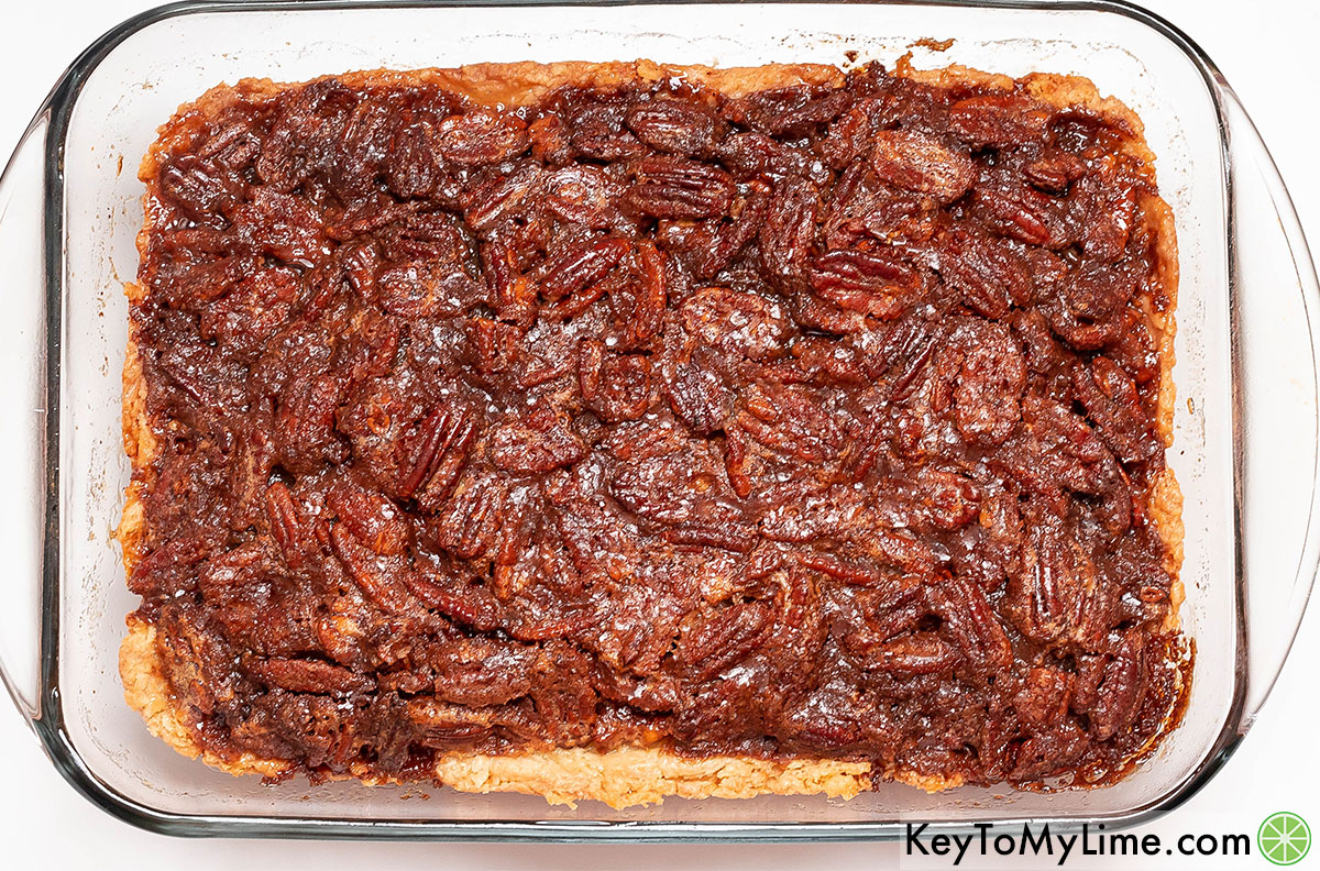 Baking the finished pecan cobbler in the oven until the crust turns golden and filling is slightly jiggly.