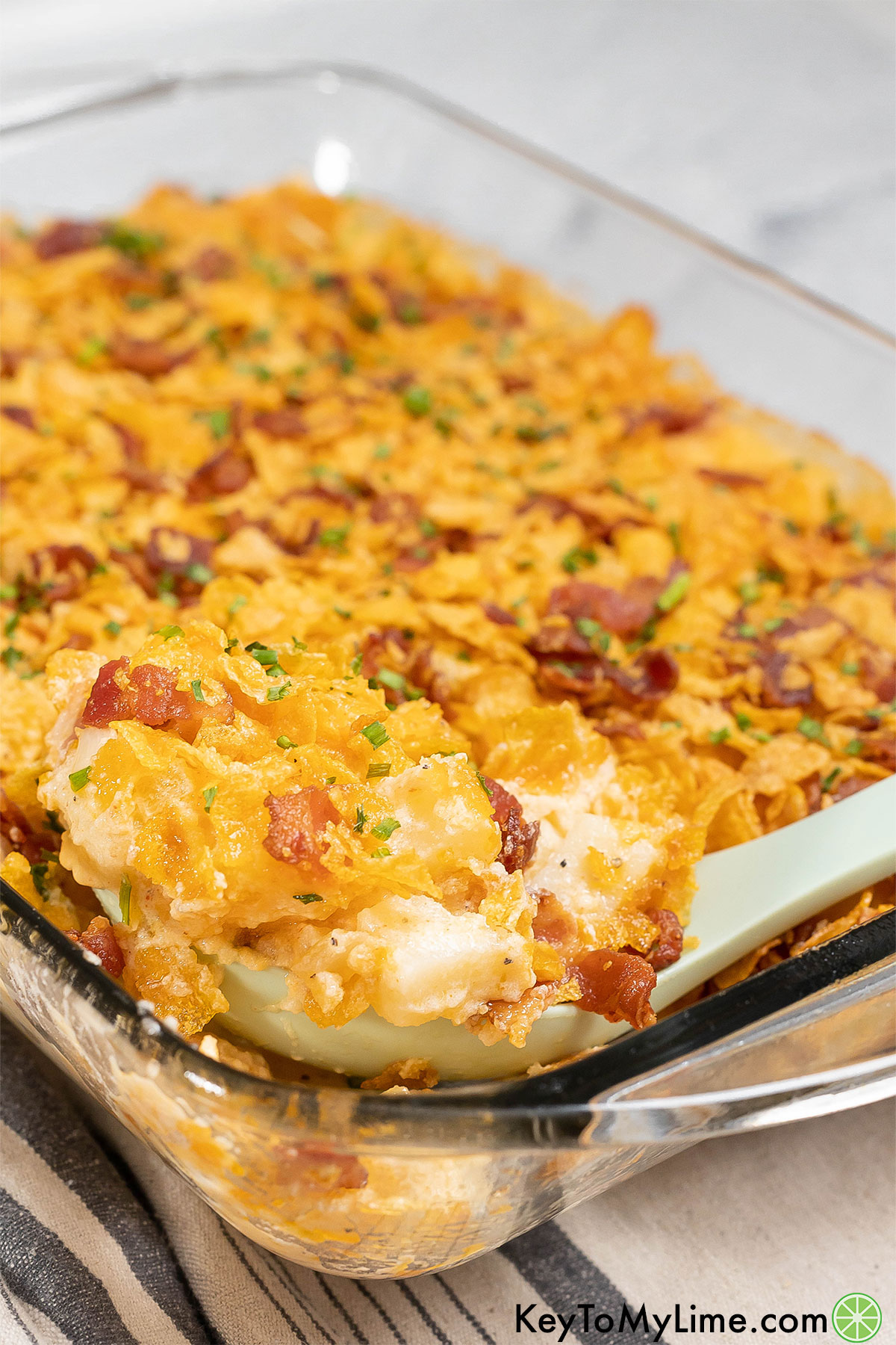 A finished potato casserole with a thick layer of cheese on top in a casserole dish.