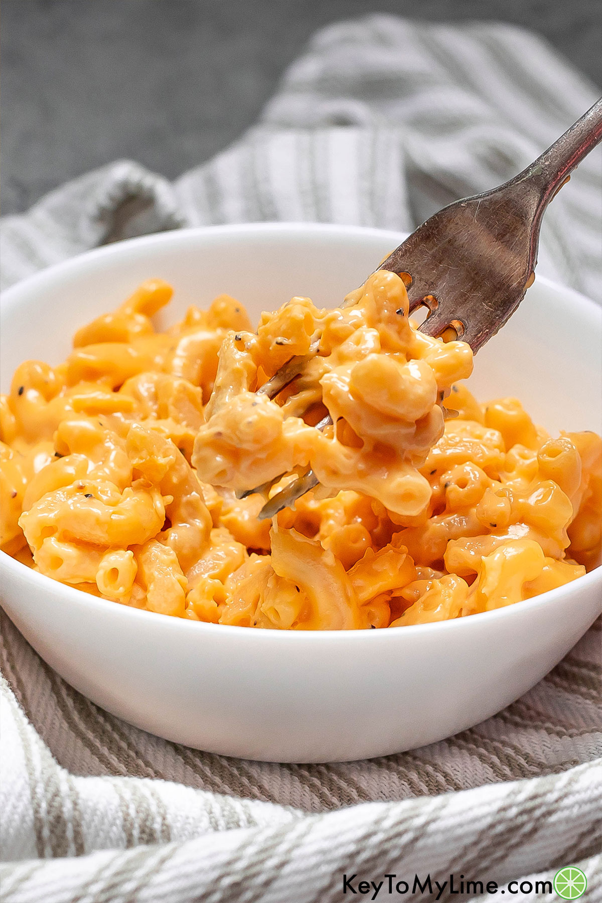 A fork with mac and cheese showing how creamy the texture is.