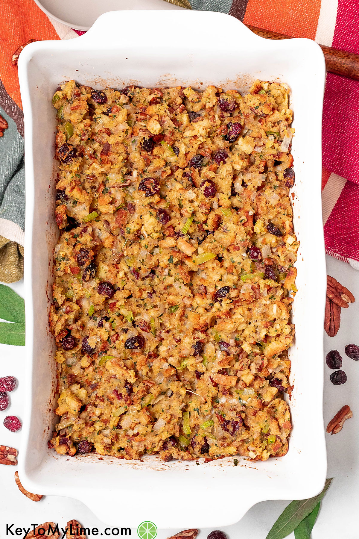 An overhead image of a fully cooked stuffing dish in a casserole dish with fresh sage on top.