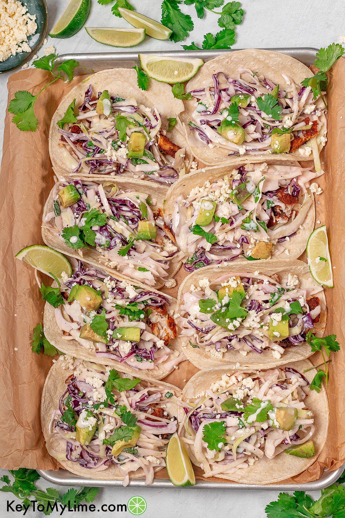 An overhead image of fish tacos garnished with avocado and feta cheese.